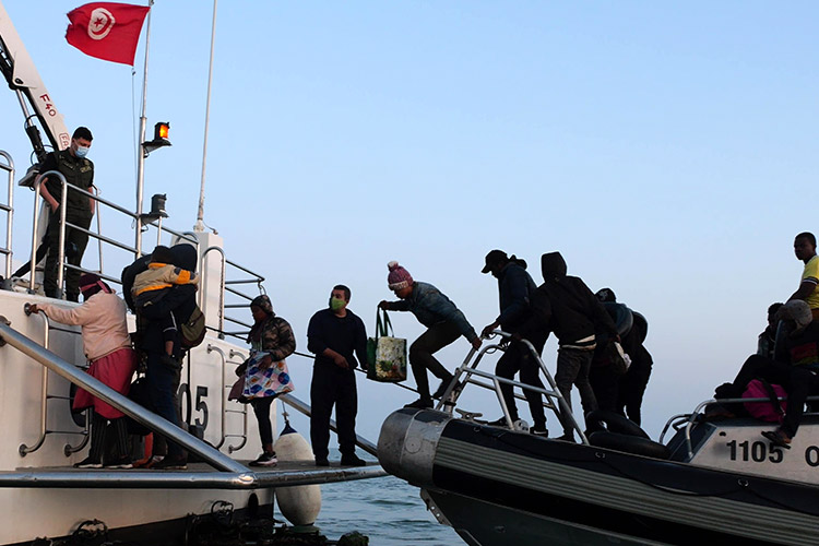 写真：密航が阻止されてチュニジア沿岸警備隊の本船に移る移民たち=2023年6月2日、チュニジア中部スファックス沖