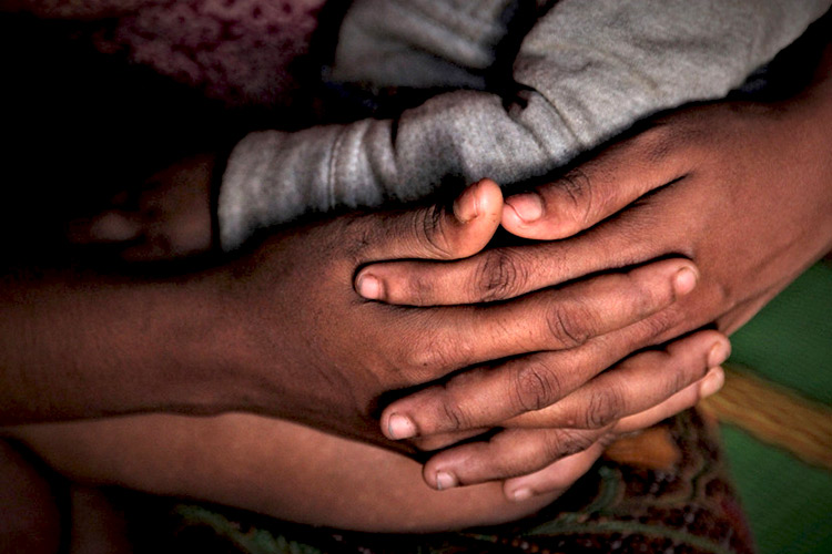 写真:乳児を抱くロヒンギャ難民の若い母親