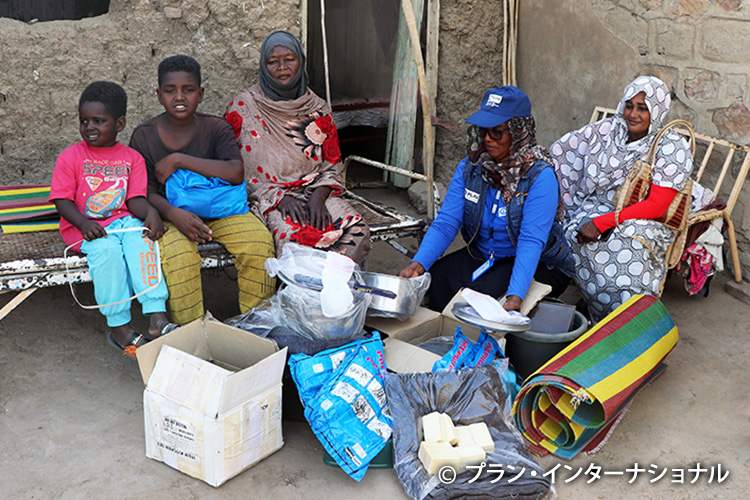 写真：避難先で救援物資を受け取る家族（スーダン）