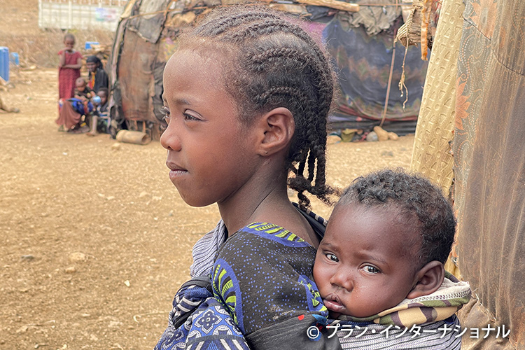 写真：母親が食料、薪、水を一日中探すため、弟を背負い、幼い兄弟姉妹5人の世話をする8歳の女の子（ケニア）