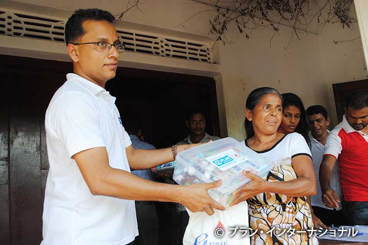 写真：被災者に衛生用品を手渡すメナカ（左）
