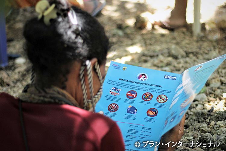 写真：プランが配付したリーフレットを読むインドネシアの女の子