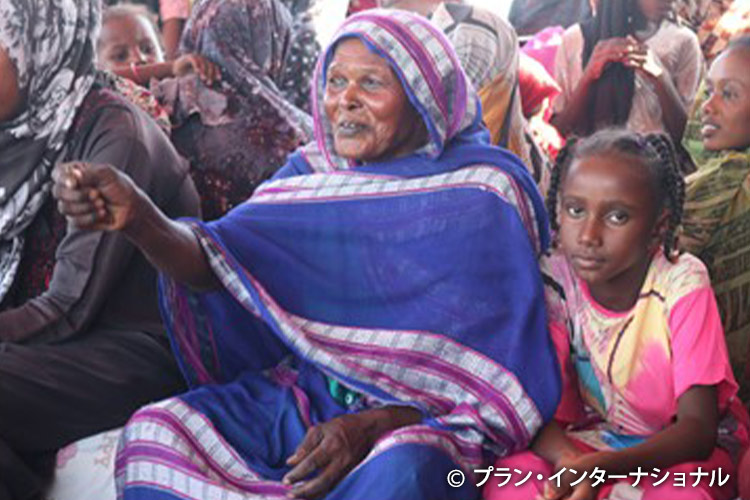 写真:孫とともに啓発セッションに参加する女性（スーダン）