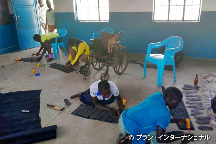 写真:廃タイヤからサンダルを作る方法を学ぶ若者たち